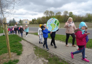 Dzieci maszerują ulicami osiedla z transparentami ekologicznymi.